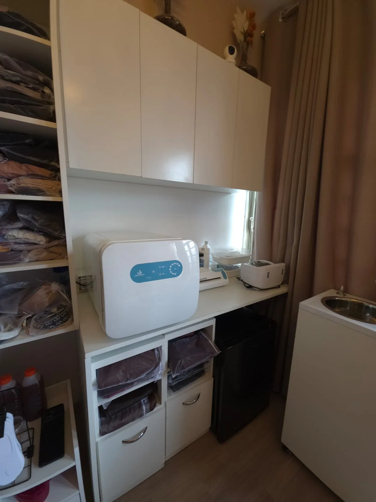 Área de esterilização do estúdio com a autoclave sobre a bancada e armários organizados