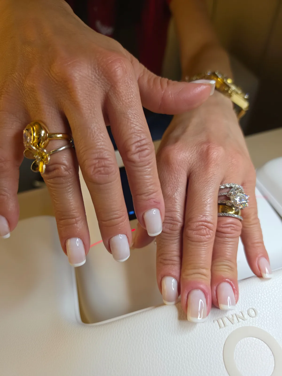 Francesinha clássica em esmaltação em gel, duas mãos com anéis sobre a cabine O NAIL