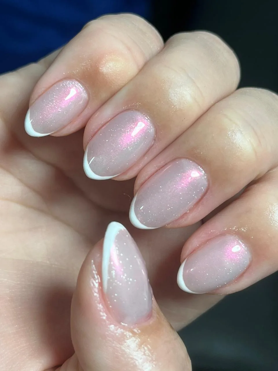 Close de unhas amendoadas com francesinha branca sobre base rosada com brilho fino